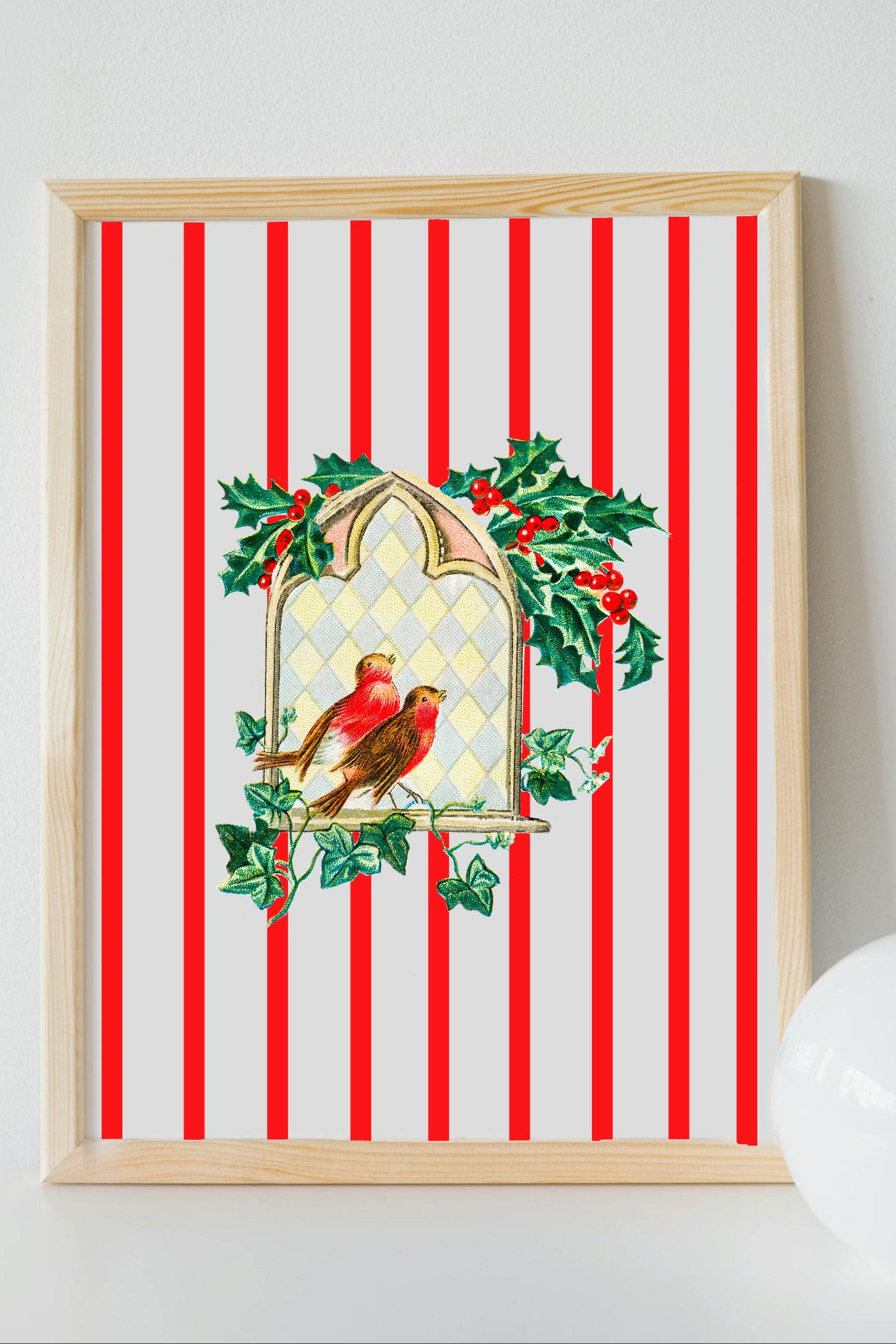 Framed artwork with a Christmas design featuring a bird and holly on a red and white striped background.